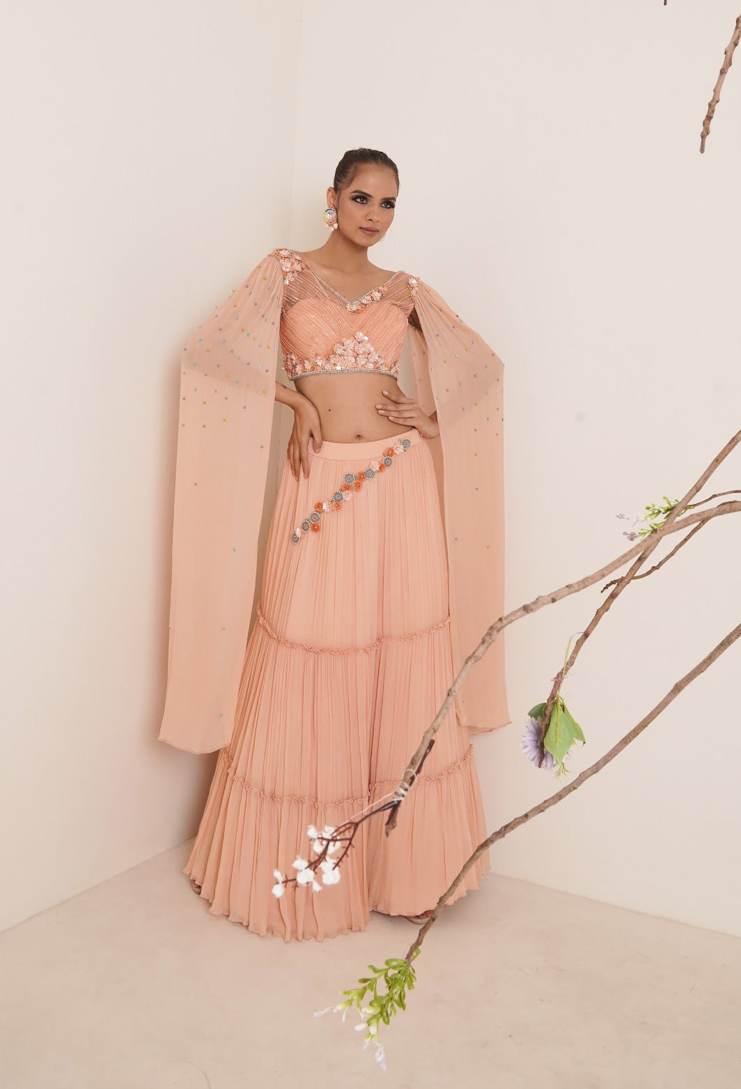 Flared peach lehenga with structured shrug.