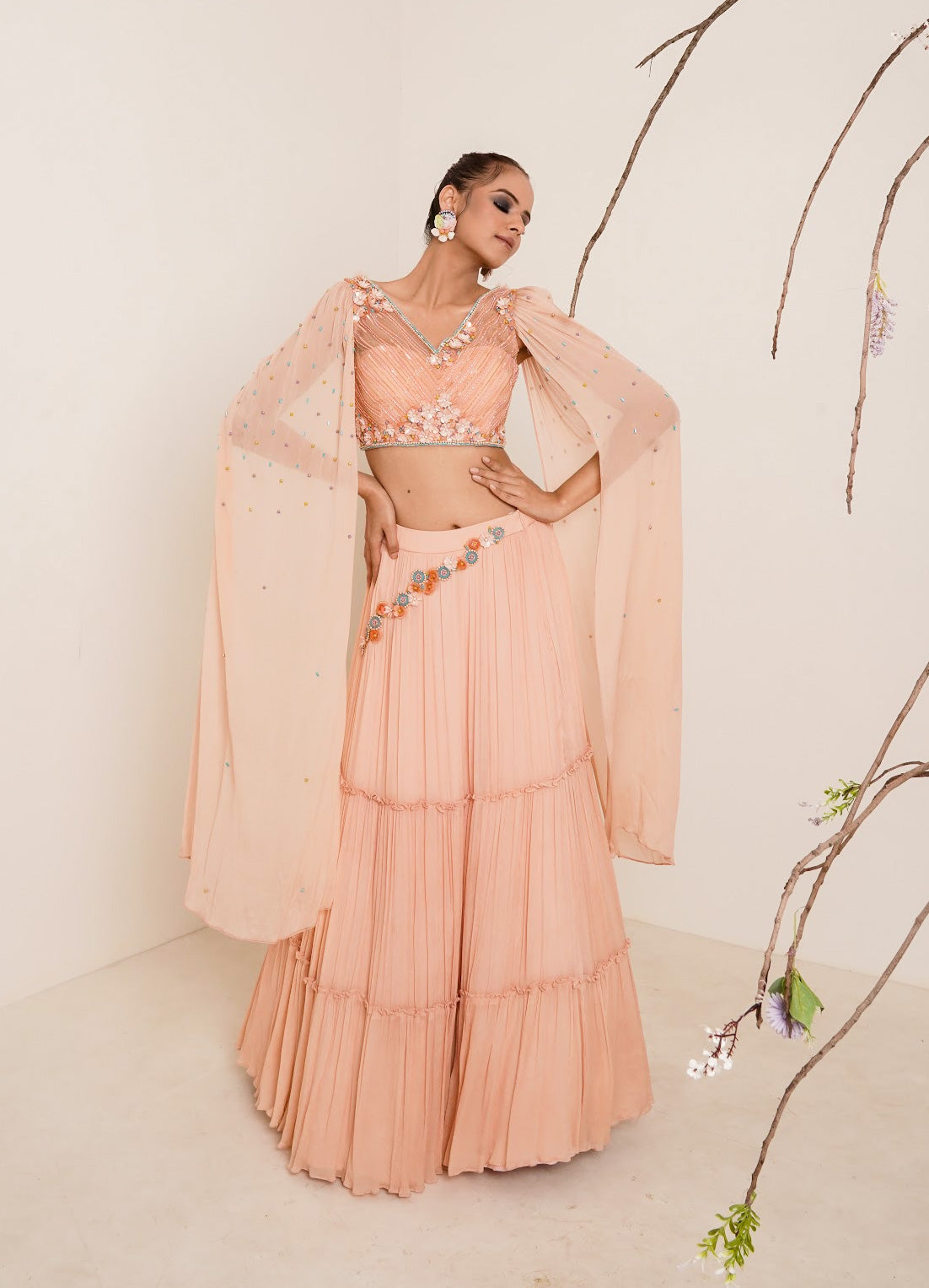 Flared peach lehenga with structured shrug.
