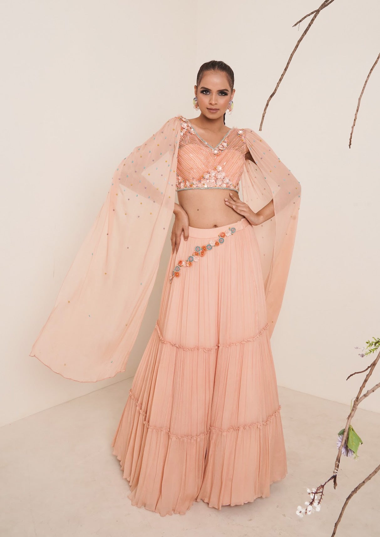 Flared peach lehenga with structured shrug.