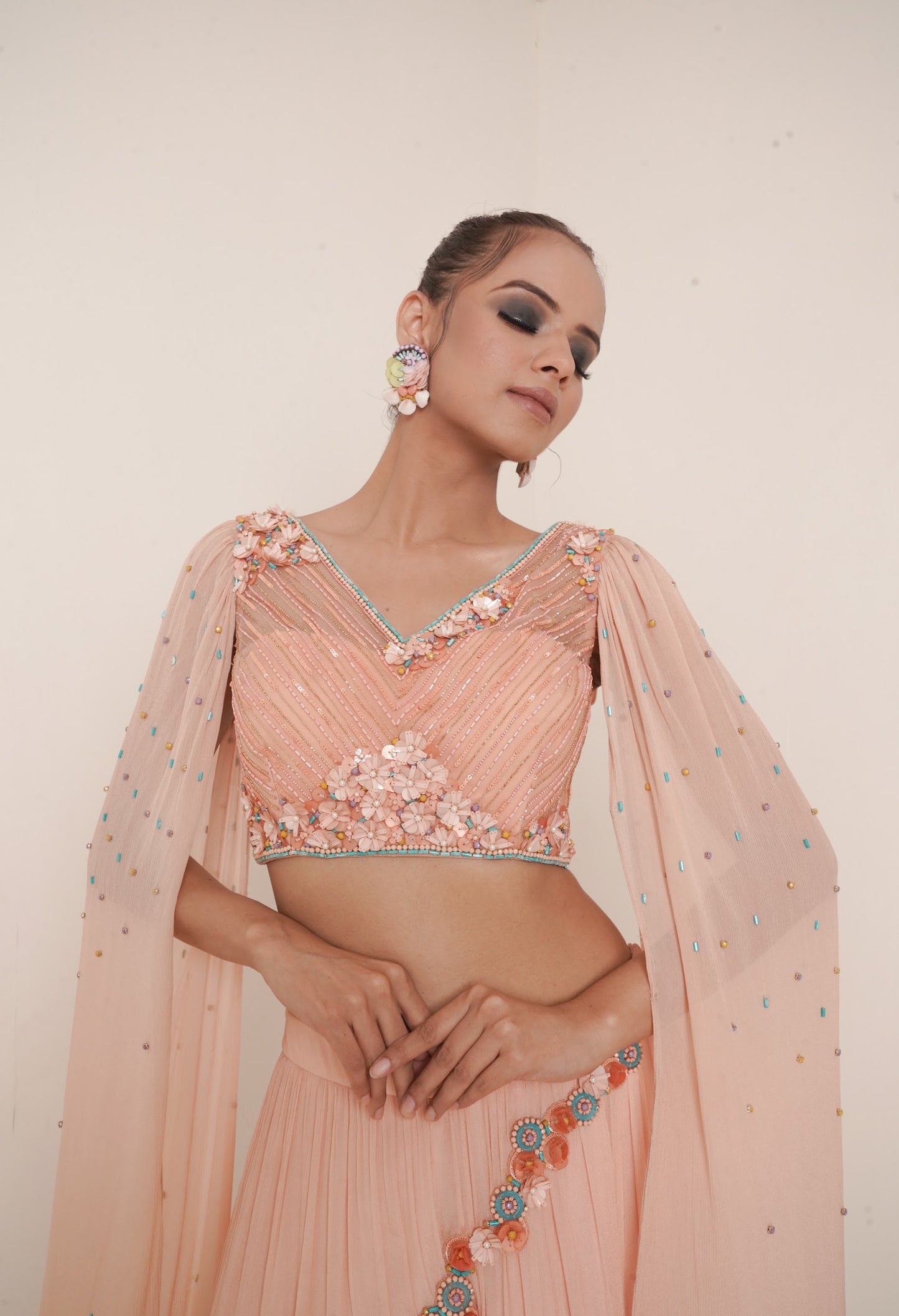 Flared peach lehenga with structured shrug.