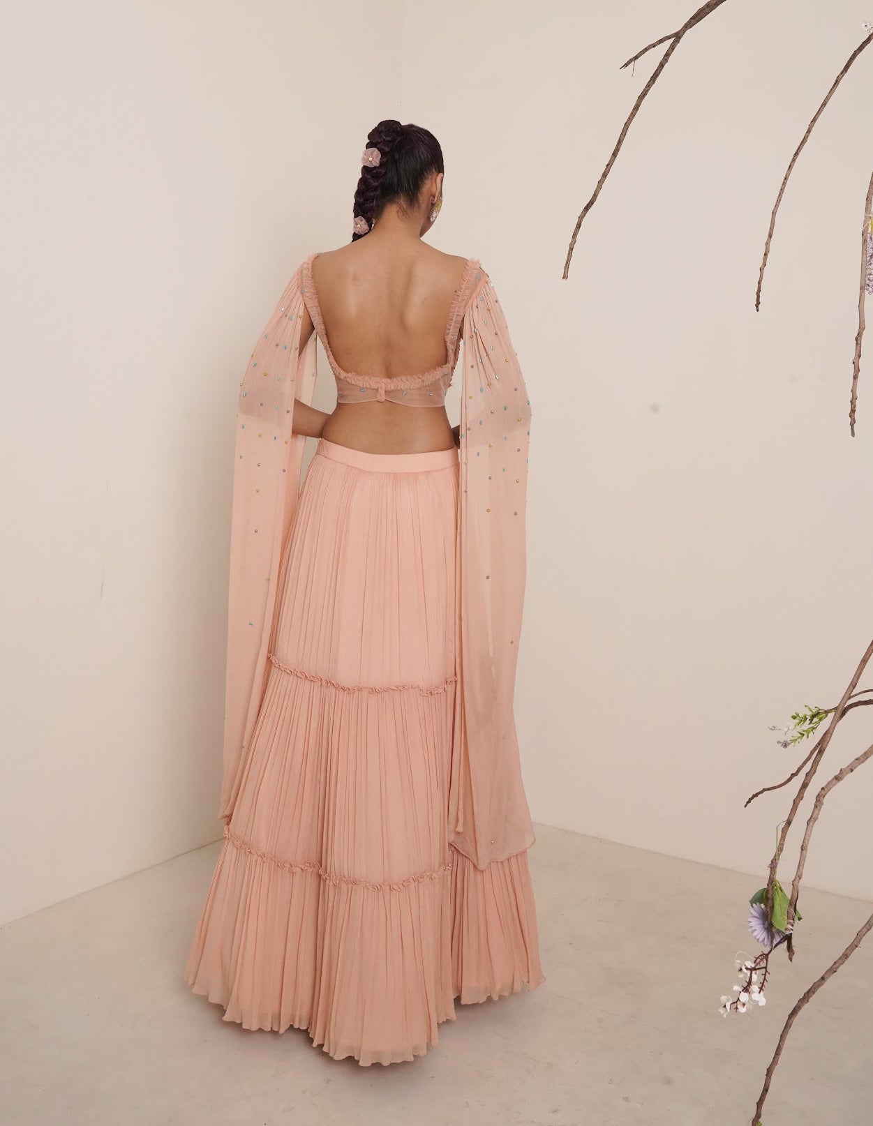Flared peach lehenga with structured shrug.