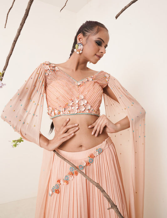 Flared peach lehenga with structured shrug.